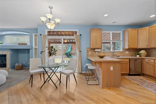 a kitchen with stainless steel appliances granite countertop a stove top oven a sink dishwasher a dining table and chairs with wooden floor