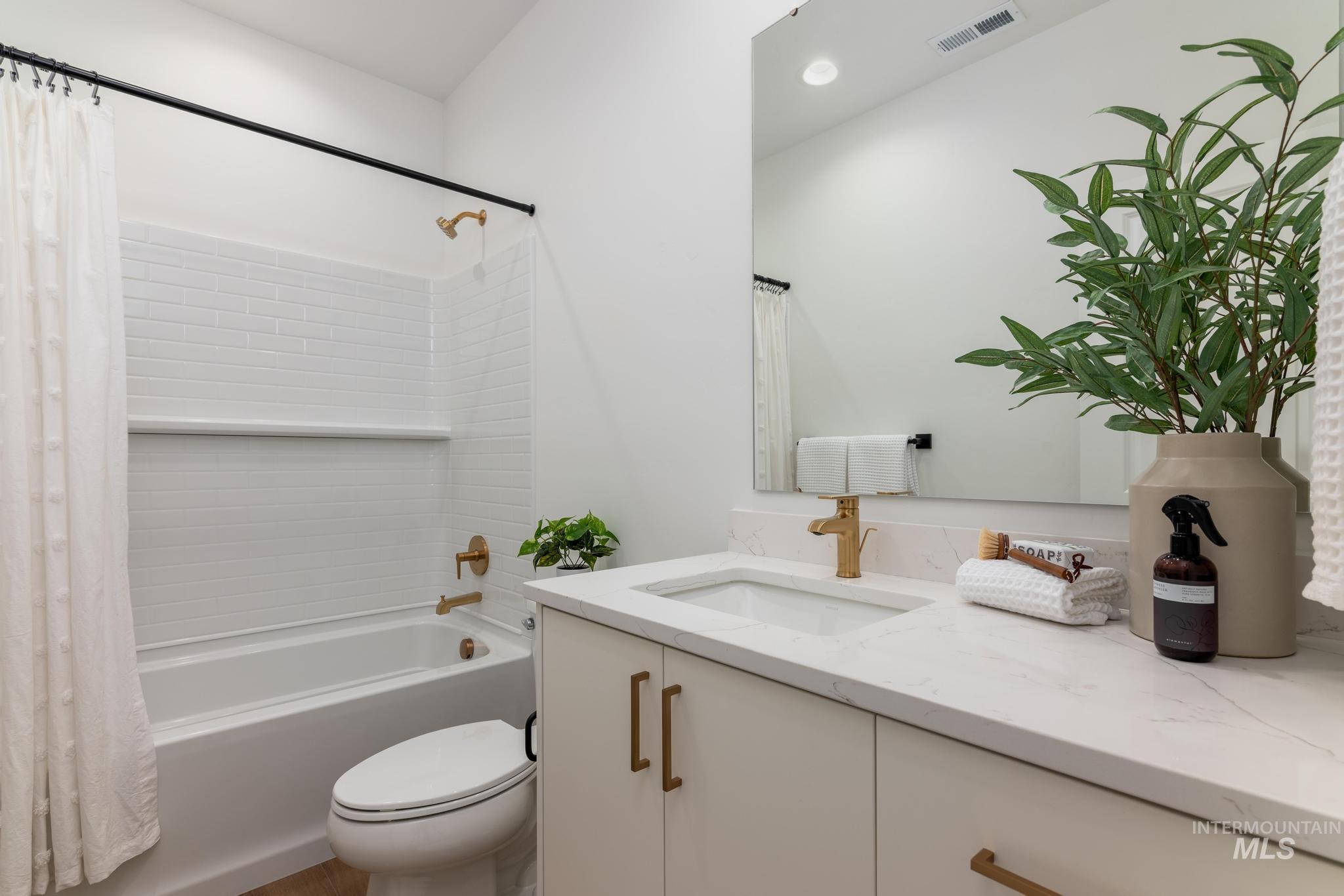 14703 Serenity Pt Street Caldwell, ID 83607 - Photo 30 of 45 Modern bathroom featuring a white subway tile tub surround with a built-in shelf, brushed brass fixtures, and a white vanity with a rectangular undermount sink