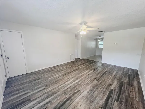 an empty room with wooden floor fan and window