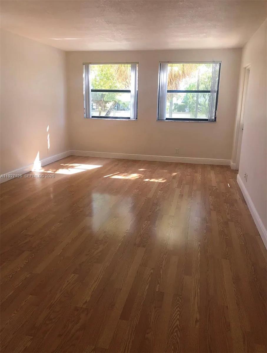 8180 Geneva Court, Unit 227 Miami, FL 33166 - Photo 4 of 11 an empty room with wooden floor and windows