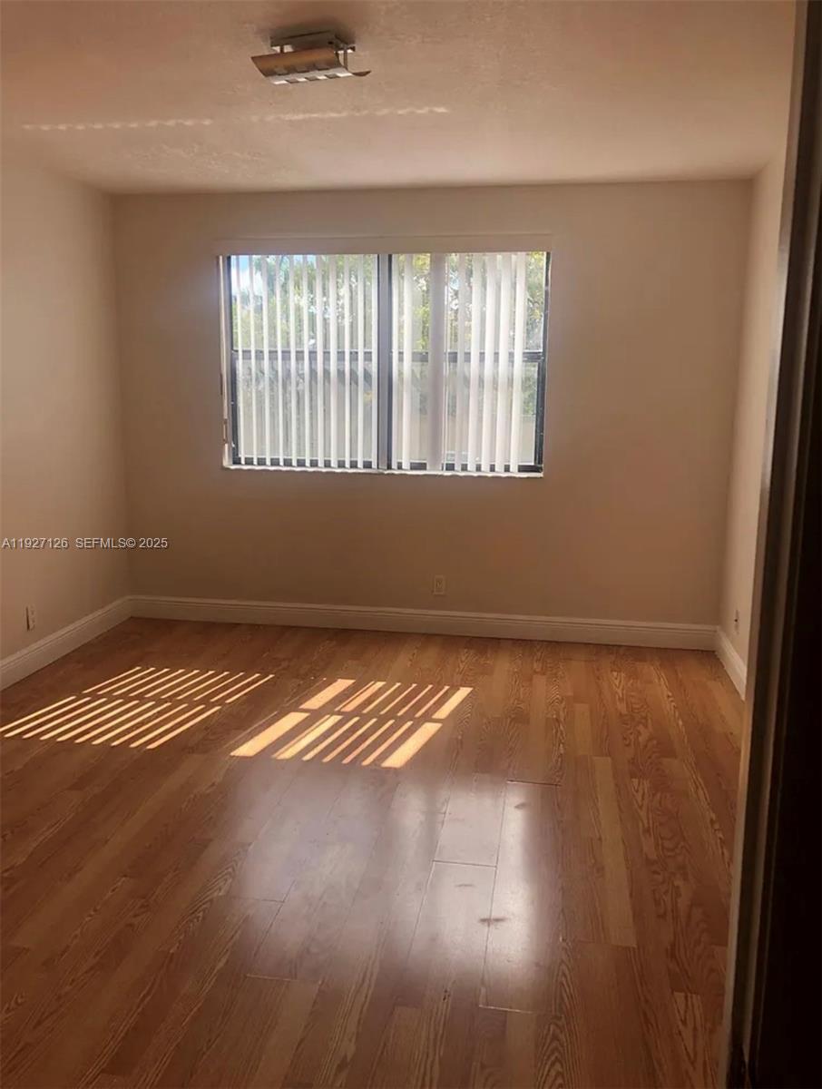 8180 Geneva Court, Unit 227 Miami, FL 33166 - Photo 7 of 11 an empty room with wooden floor and windows