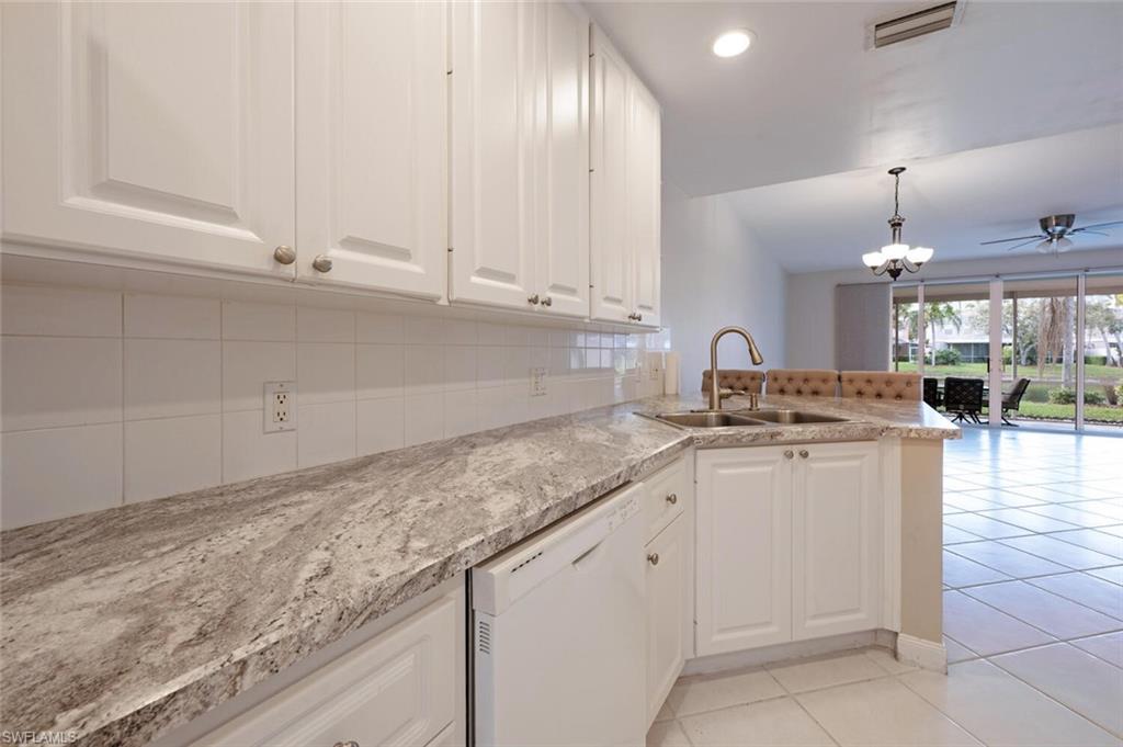 5417 Cove Circle, Unit 112 Naples, FL 34119 - Photo 11 of 37 a kitchen with granite countertop white cabinets and white appliances
