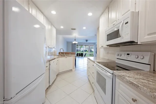 a kitchen with white cabinets and appliances
