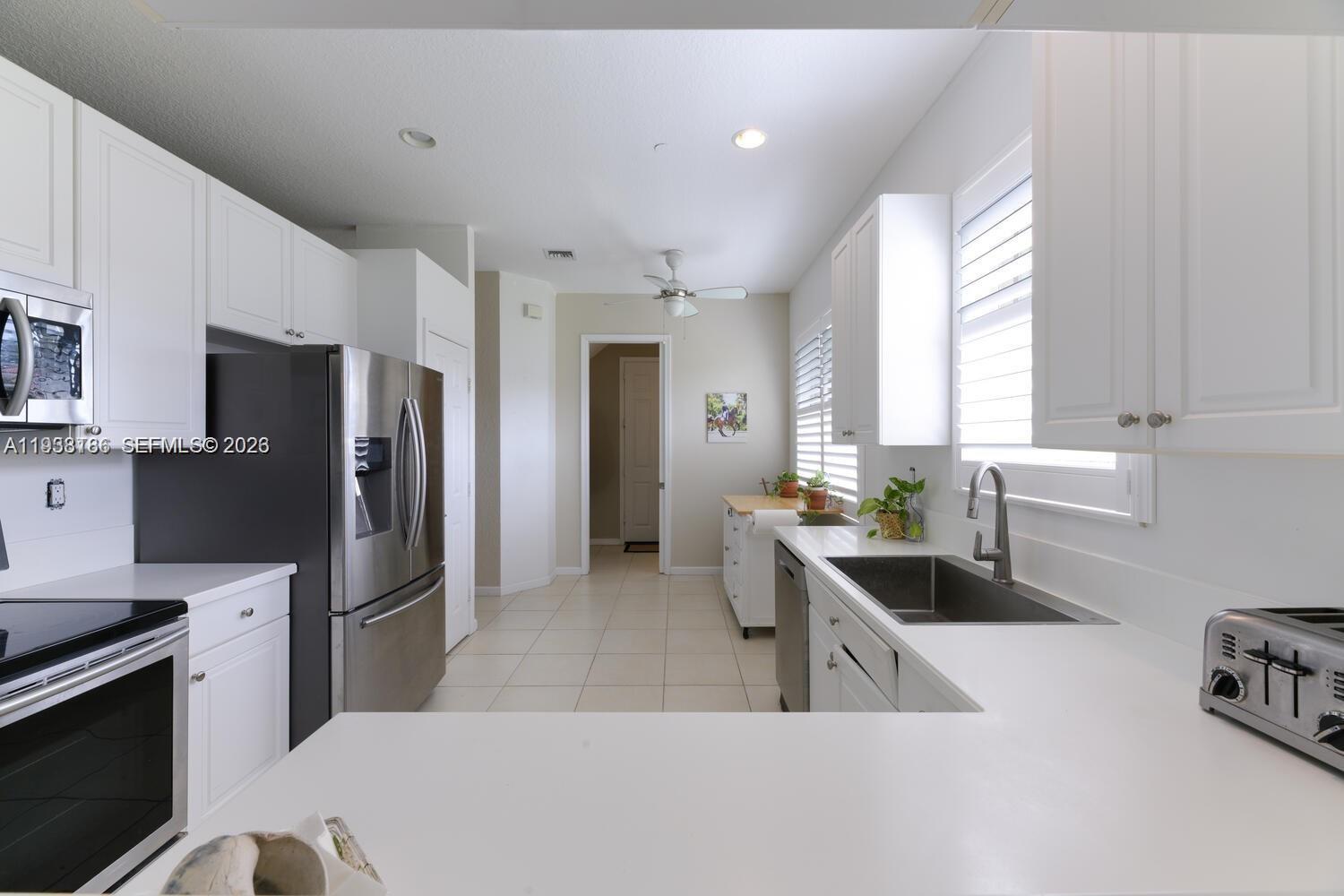 250 Southwest Walking Path, Unit 250 Stuart, FL 34997 - Photo 13 of 29 a kitchen with stainless steel appliances a refrigerator a sink a stove a microwave a counter space and cabinets