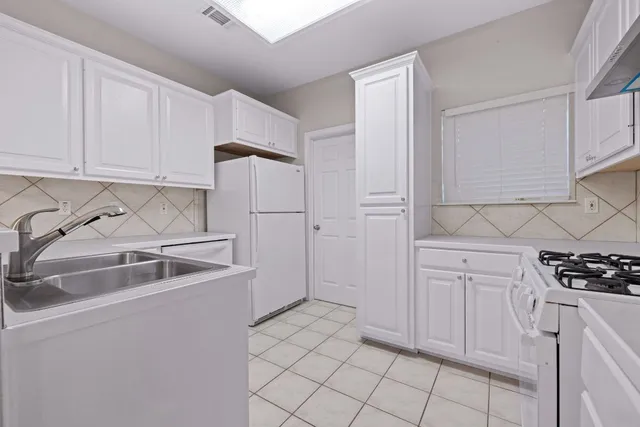 a kitchen with white cabinets and white appliances