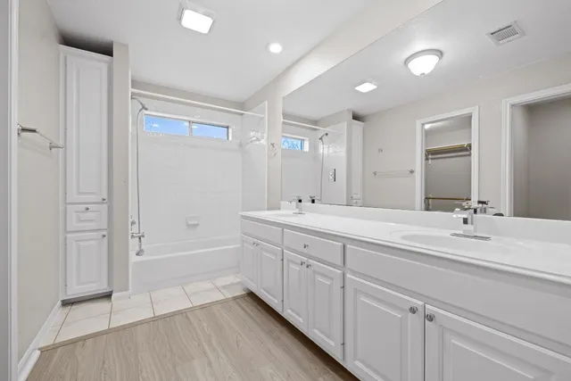 a spacious bathroom with a double vanity sink a mirror and a bathtub