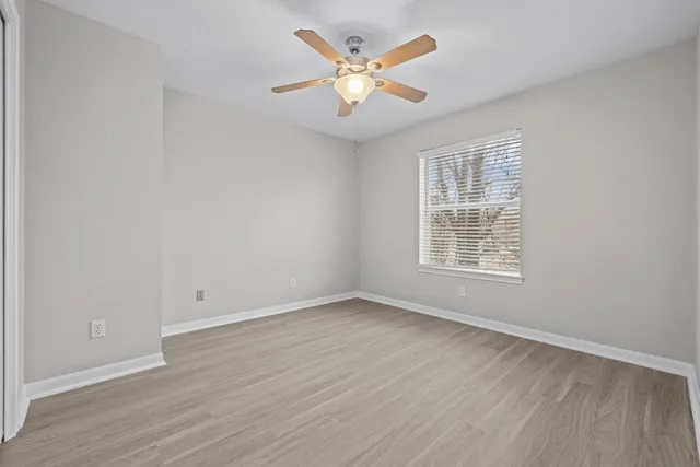 an empty room with wooden floor and ceiling fan