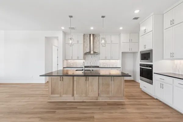 a large white kitchen with kitchen island and stainless steel appliances