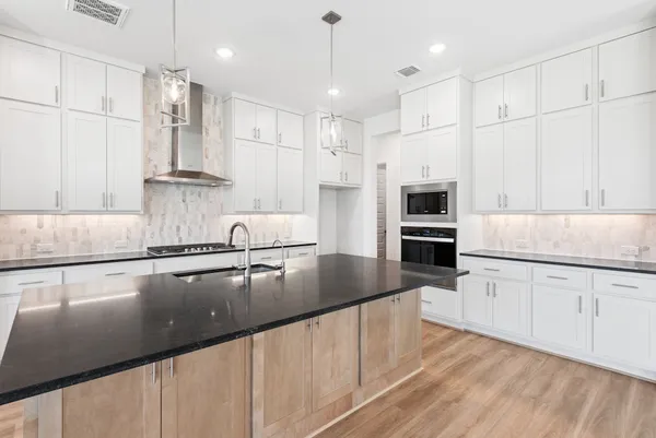 a kitchen with stainless steel appliances granite countertop a sink refrigerator and cabinets