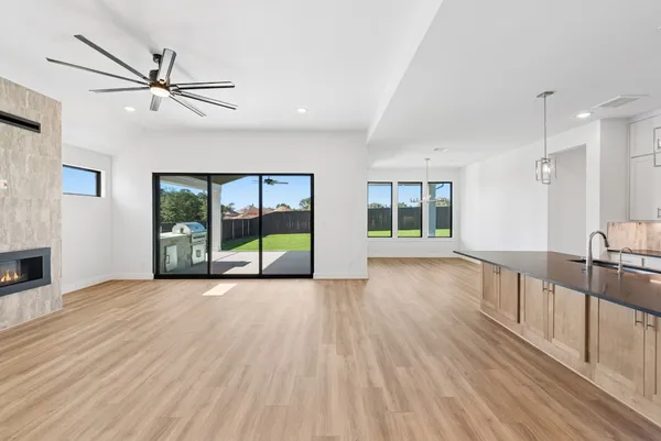 a view of a livingroom with furniture wooden floor a ceiling fan and windows