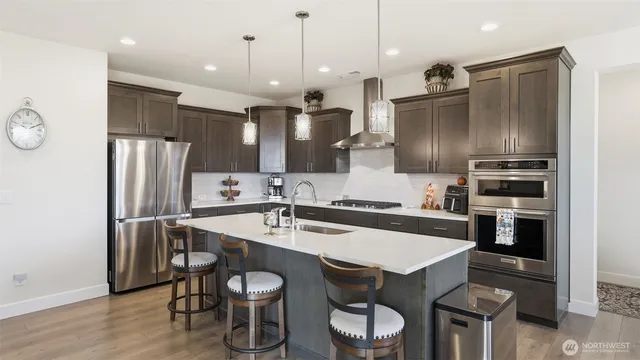 a kitchen with stainless steel appliances a refrigerator a stove a sink and chairs