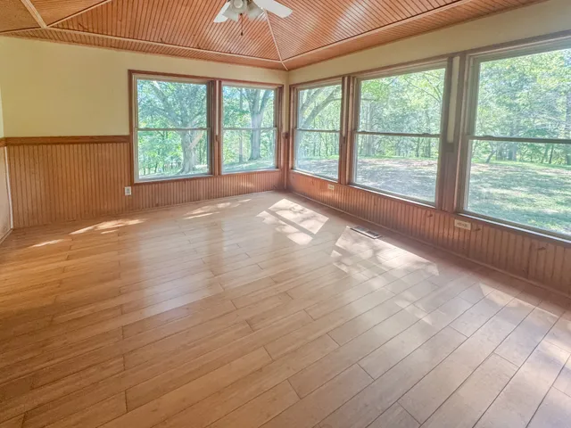 a view of an empty room with a window and wooden floor