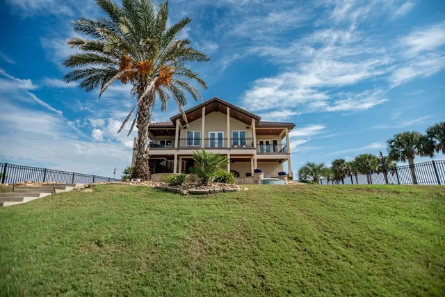 a view of a house with a big yard and palm trees