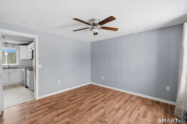 a view of empty room with wooden floor and ceiling fan
