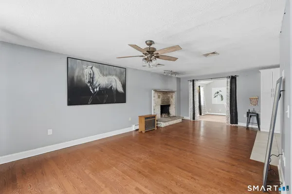 a view of an empty room with window and wooden floor