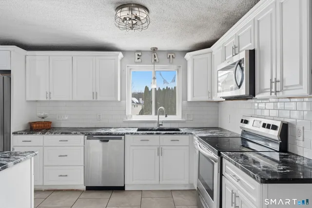 a kitchen with granite countertop cabinets stainless steel appliances and a sink