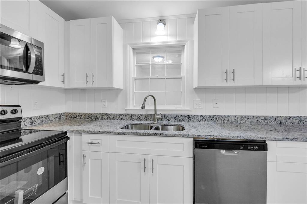 1586 Kings Road Marietta, GA 30062 - Photo 17 of 66 a kitchen with stainless steel appliances granite countertop a sink dishwasher a stove and a microwave oven with white cabinets