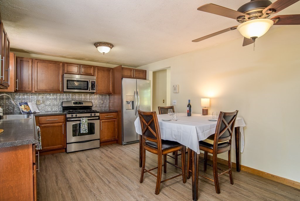 73 Sawmill Road Springfield, MA 01118 - Photo 7 of 30 a kitchen with stainless steel appliances granite countertop a stove a refrigerator a sink a dining table and chairs with wooden floor