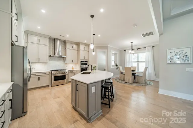 a kitchen with kitchen island a stove a sink a refrigerator and white cabinets with wooden floor