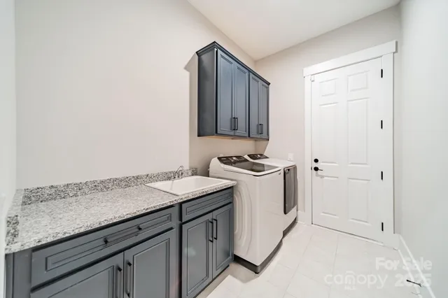 a utility room with granite countertop cabinets and sink