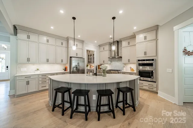 a kitchen with stainless steel appliances kitchen island granite countertop a dining table chairs and white cabinets
