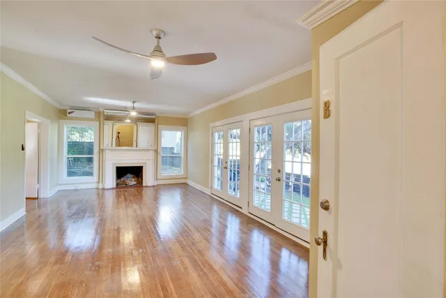 a view of an empty room with wooden floor fireplace and a window