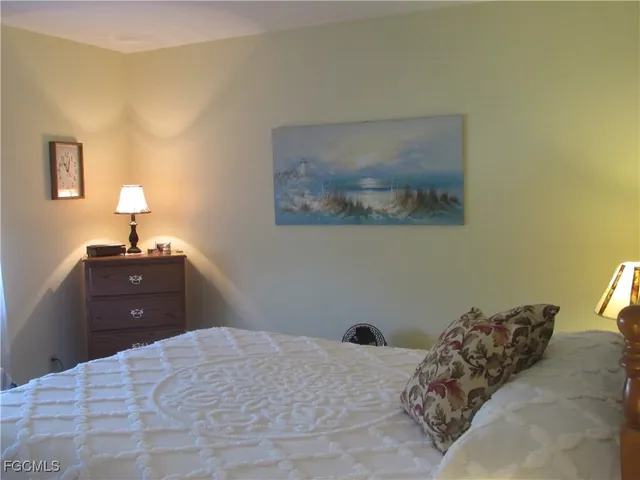 a bedroom with a bed and a lamp on dresser