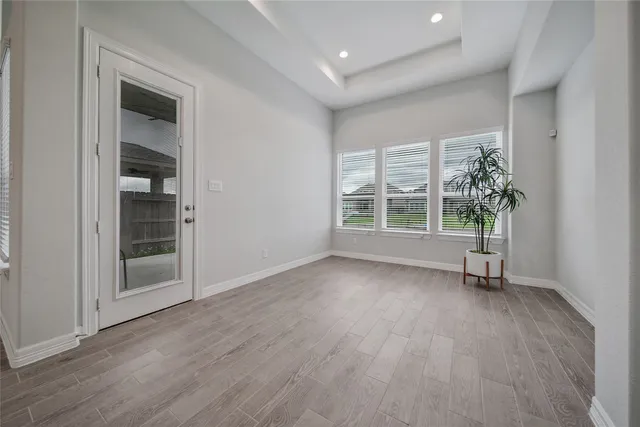 an empty room with wooden floor and windows