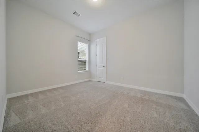 an empty room with windows and refrigerator in it