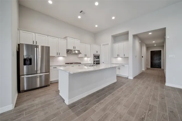 a kitchen with kitchen island a refrigerator sink and cabinets