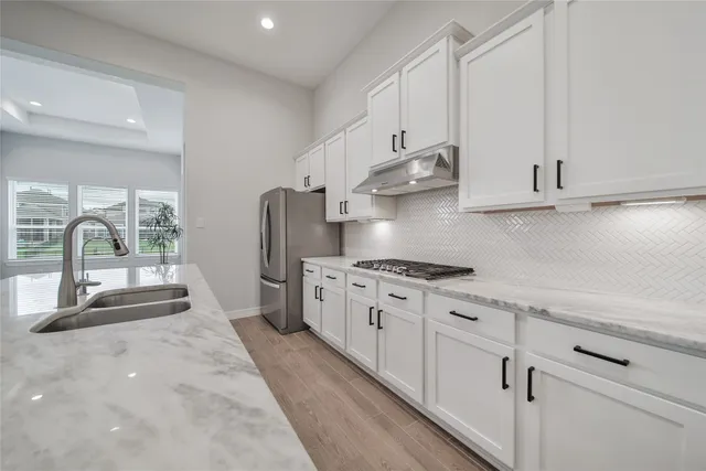 a kitchen with stainless steel appliances granite countertop a stove a sink and white cabinets