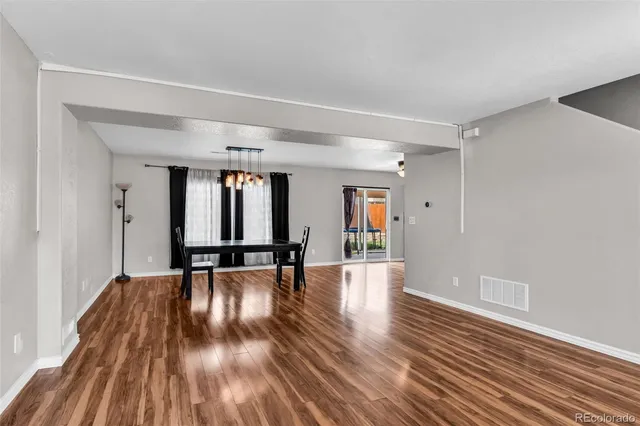 a view of an empty room with wooden floor and window