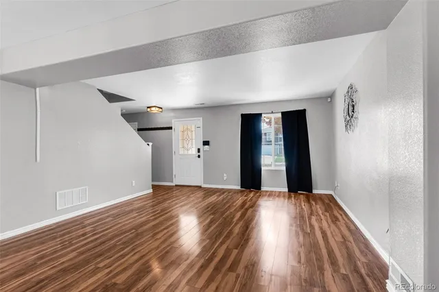 a view of a big room with wooden floor and windows