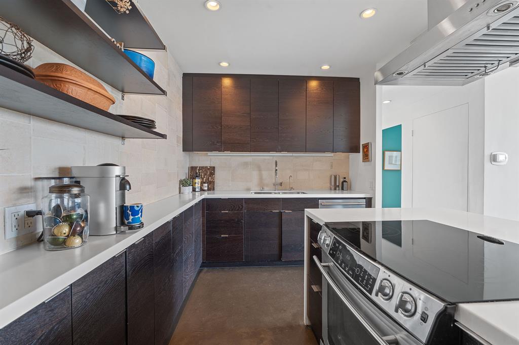 1801 Lavaca Street, Unit 12K Austin, TX 78701 - Photo 10 of 27 Kitchen with open shelves, electric range, exhaust hood, concrete floors, and backsplash