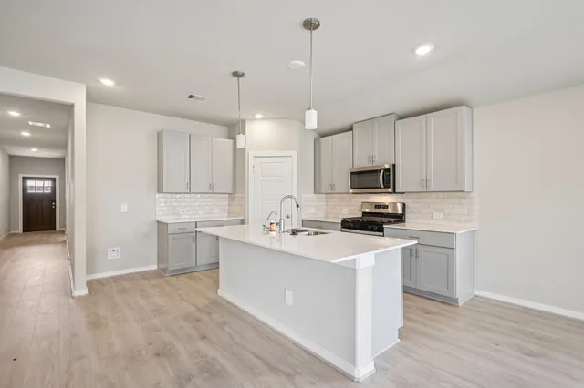 a kitchen with a sink a stove a refrigerator and white cabinets