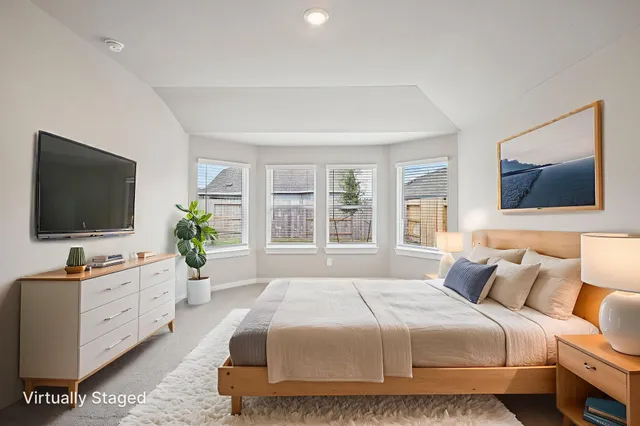 a bedroom with a bed a flat screen tv and a potted plant