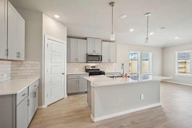 a kitchen with kitchen island a sink stainless steel appliances and cabinets