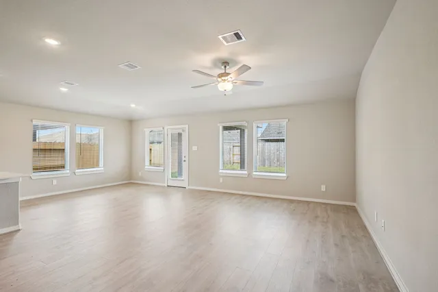 a view of an empty room with a window and wooden floor