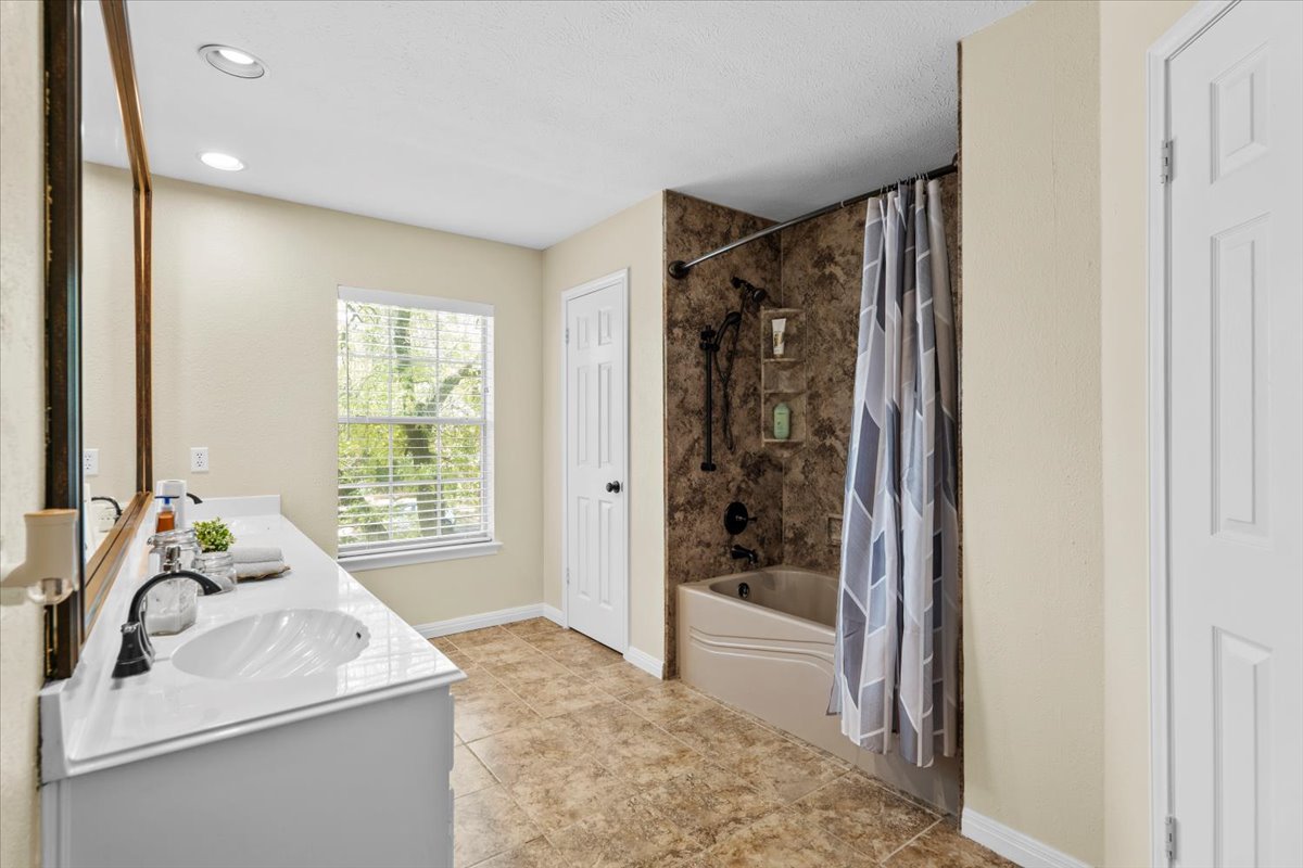 10116 Pinehurst Drive Austin, TX 78747 - Photo 25 of 37 Bathroom featuring double vanity, shower / tub combo with curtain, recessed lighting, and tile patterned floors