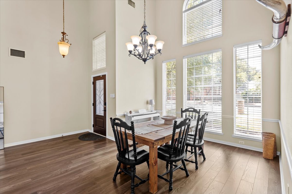 10116 Pinehurst Drive Austin, TX 78747 - Photo 3 of 37 Dining area featuring dark wood finished floors, healthy amount of natural light, a high ceiling, and a chandelier