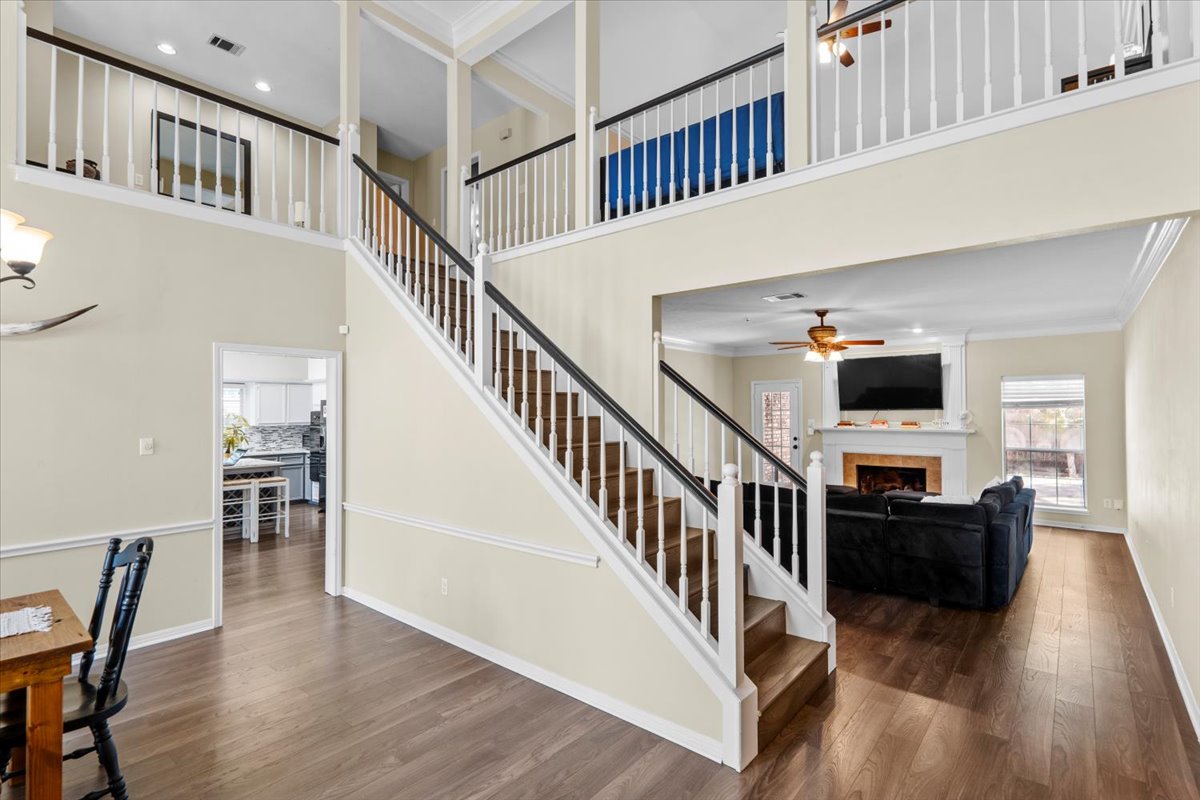 10116 Pinehurst Drive Austin, TX 78747 - Photo 4 of 37 Stairs with a tiled fireplace, ornamental molding, wood finished floors, a towering ceiling, and recessed lighting