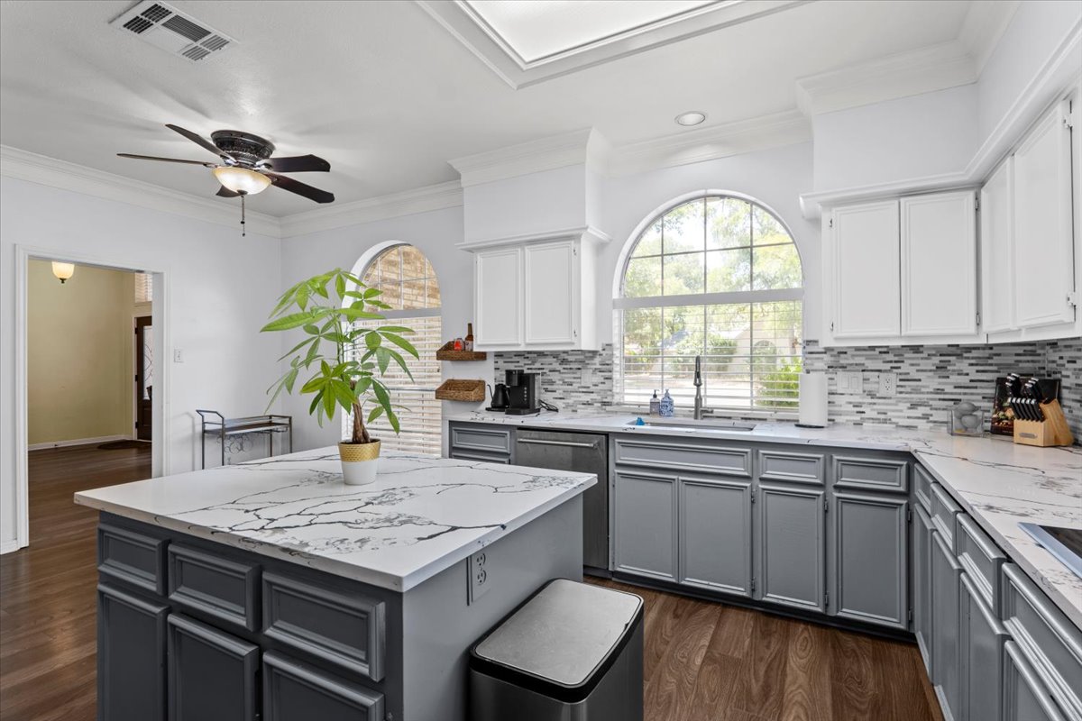 10116 Pinehurst Drive Austin, TX 78747 - Photo 5 of 37 Kitchen with gray cabinetry, crown molding, dark wood finished floors, a ceiling fan, and a kitchen island