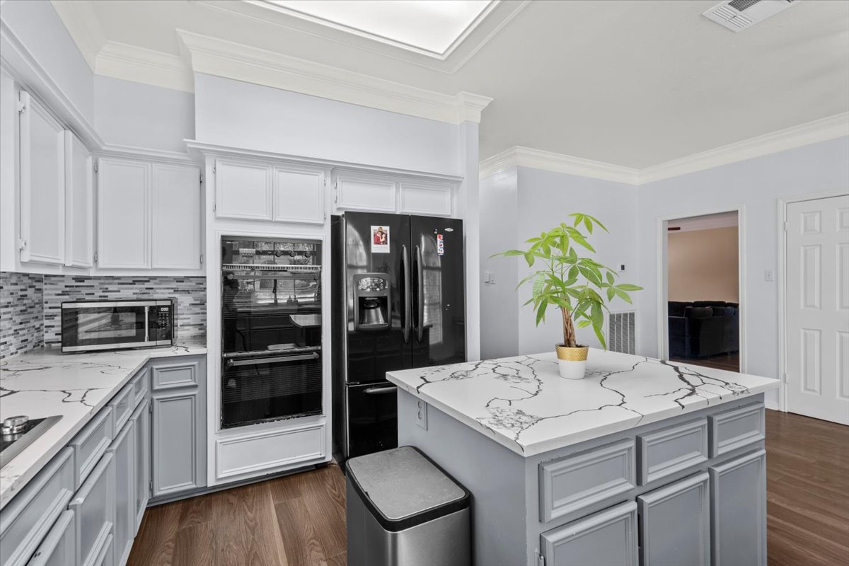 10116 Pinehurst Drive Austin, TX 78747 - Photo 8 of 37 Kitchen featuring ornamental molding, black appliances, gray cabinetry, dark wood-style flooring, and light stone countertops