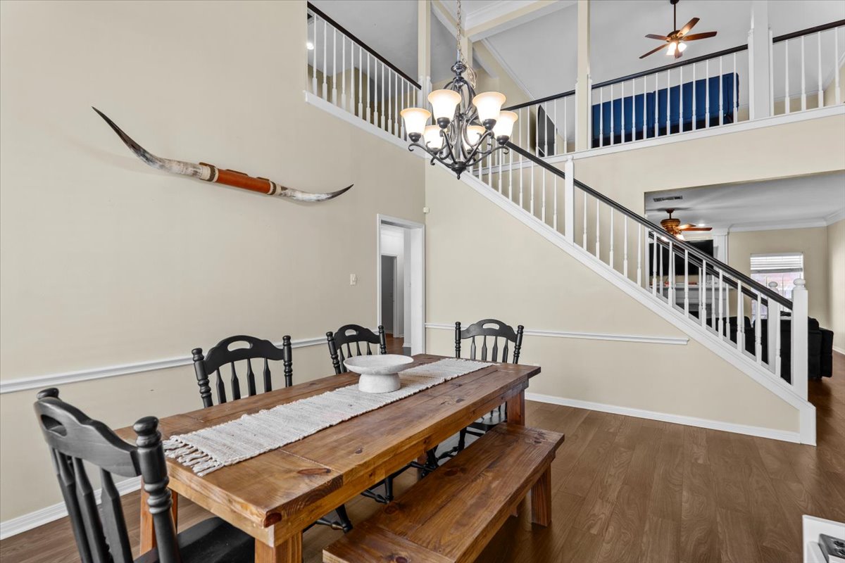 10116 Pinehurst Drive Austin, TX 78747 - Photo 9 of 37 Dining area with a ceiling fan, wood finished floors, a high ceiling, stairway, and a chandelier