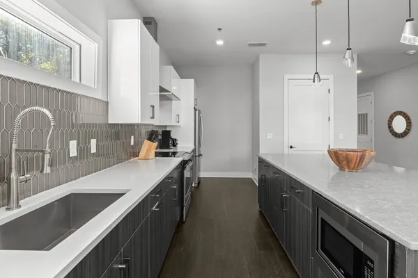 a kitchen with kitchen island granite countertop a sink a stove and a wooden floors