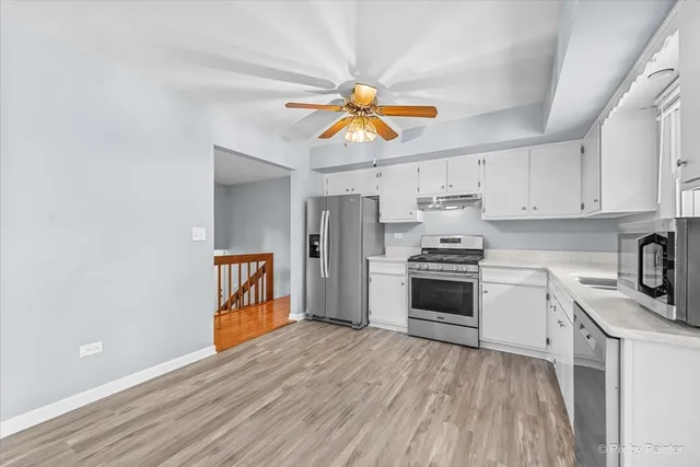 a kitchen with granite countertop a stove top oven a sink dishwasher and a refrigerator with wooden floor