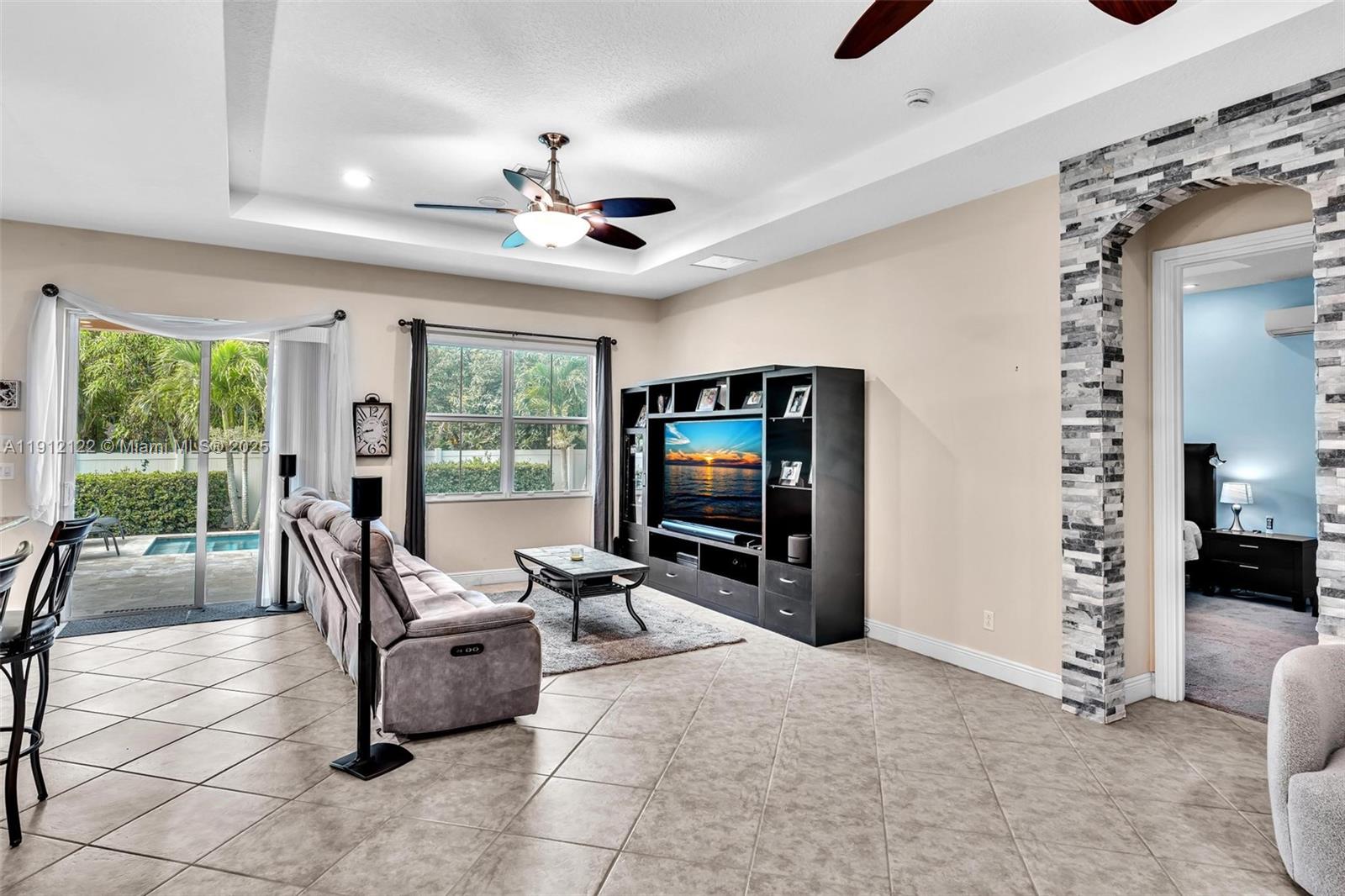 13220 Southwest 13th Street Davie, FL 33325 - Photo 22 of 65 a living room with furniture a flat screen tv and a floor to ceiling window