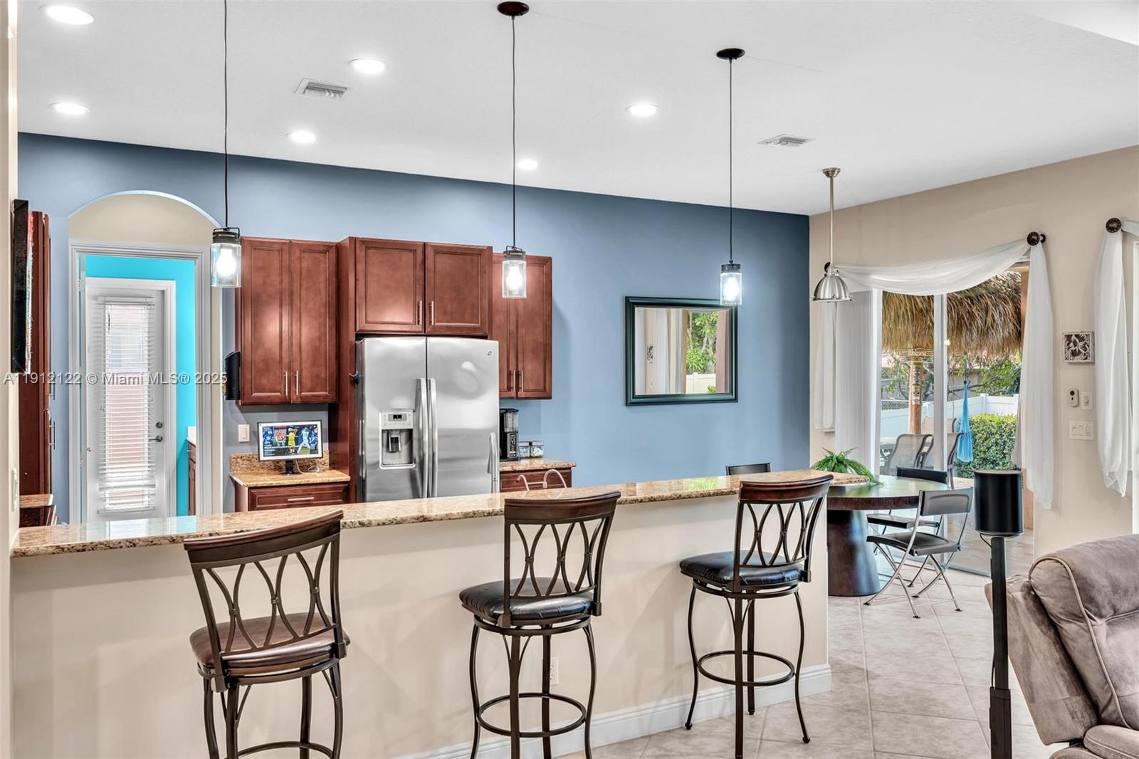 13220 Southwest 13th Street Davie, FL 33325 - Photo 27 of 65 a dinning area with stainless steel appliances kitchen island granite countertop a dining table chairs refrigerator and sink