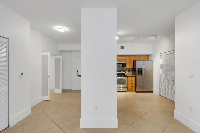 a view of empty room with kitchen and refrigerator