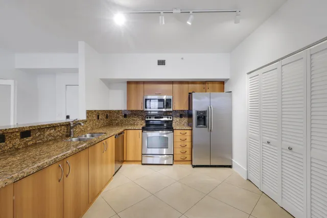 a kitchen with stainless steel appliances granite countertop a sink and a refrigerator